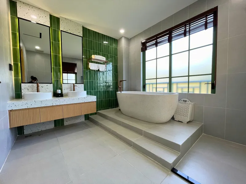 Thiết kế nội thất phòng tắm cao cấp với bồn tắm sang trọng và tường ốp gạch xanh rêu do SMJA Home thực hiện