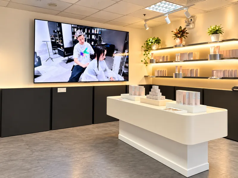 Khu vực trưng bày sản phẩm sang trọng tại văn phòng ÉTé với kệ gắn đèn LED, bục trưng bày giữa phòng và màn hình lớn trình chiếu.